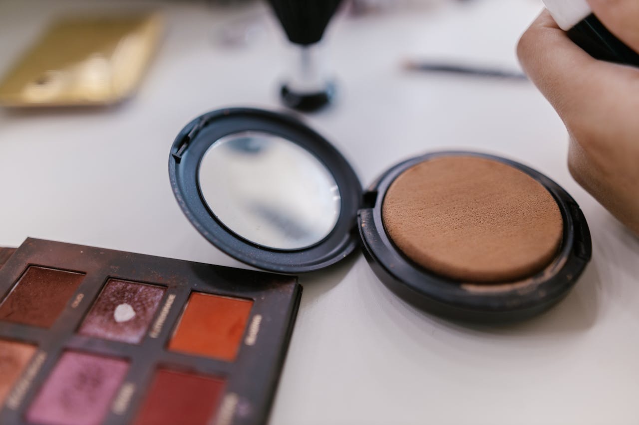 Detailed shot of makeup palette and compact powder on a table, perfect for beauty related content.