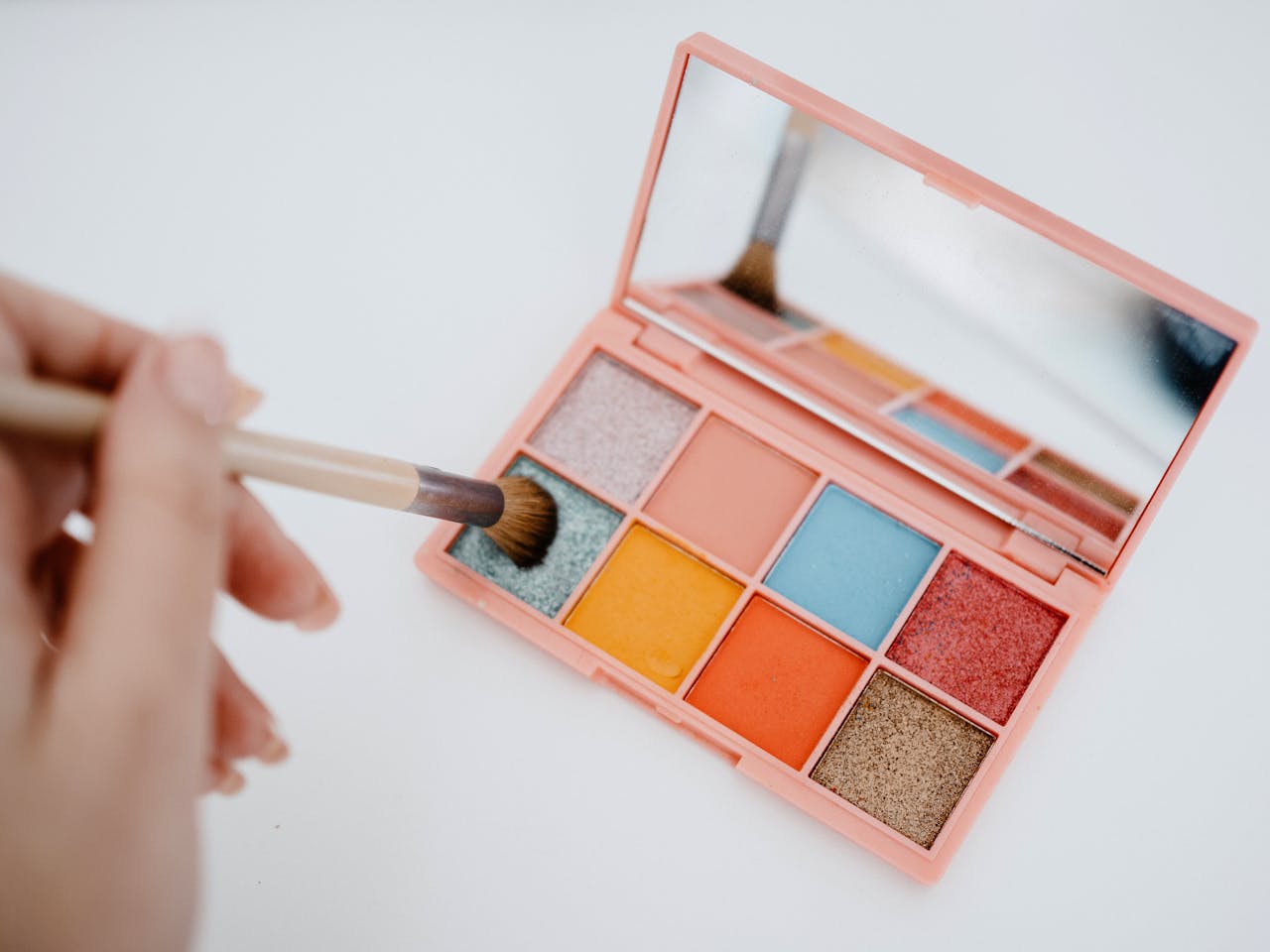 Colorful eyeshadow palette with a makeup brush on a white background.