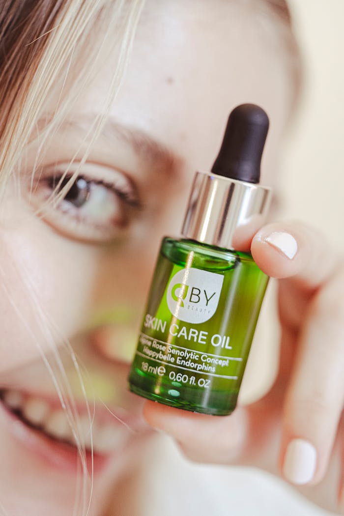Close-up of smiling woman holding a green skincare oil bottle with dropper.