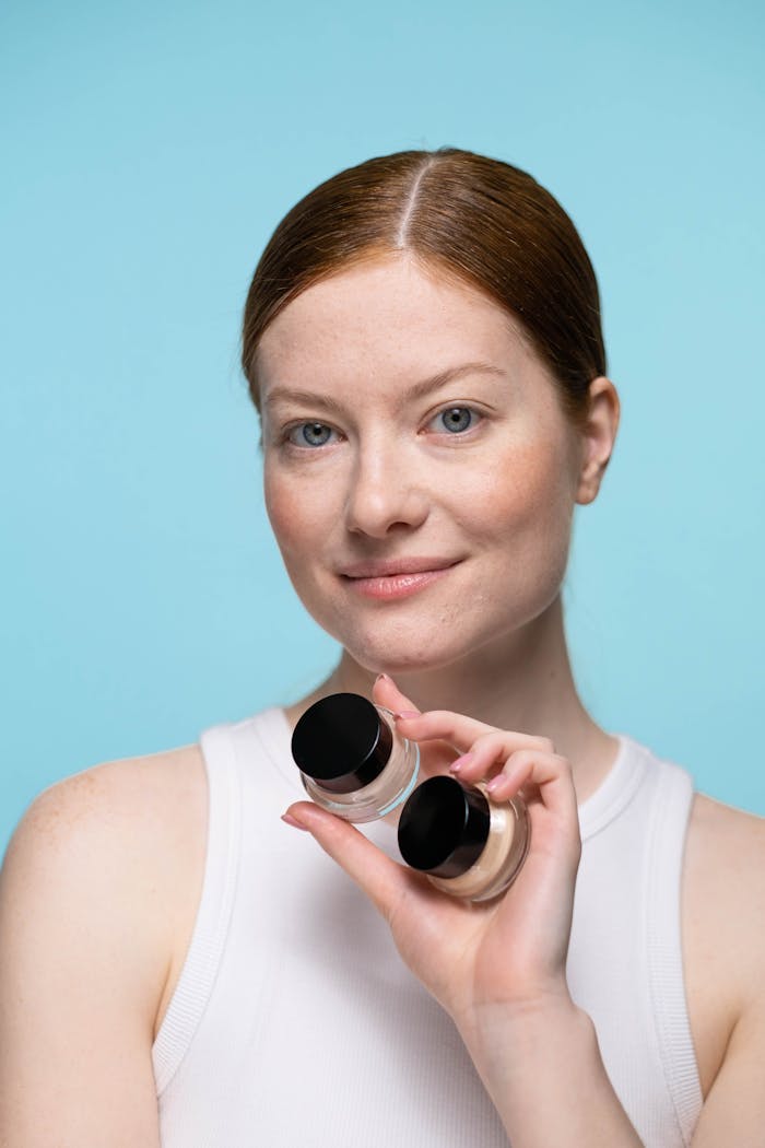 Portrait of a woman showcasing cosmetic products against a blue background.